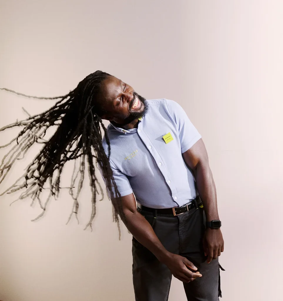 Picture of Edward smiling and throwing his hair to the side wearing a Waitrose uniform.