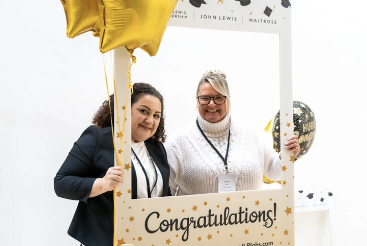 Two JLP apprentices post in a Congratulations frame